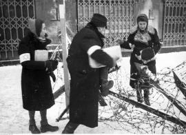Troje Żydów przechodzi przez zasieki z drutów kolczastych w getcie. (Fot. NAC)